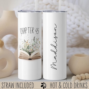 May include: White stainless steel tumbler with a black and white floral design and the text "Chapter 45". The tumbler is next to a white stainless steel tumbler with the text "Madison". Both tumblers have a straw included and are for hot and cold drinks.