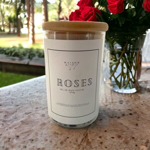 Könnte beinhalten: Ein Glasgefäß mit Bambusdeckel, gefüllt mit Badesalz. Das Etikett lautet "Maison  Handma  Roses  Sel de Bain Fleuri  450g".