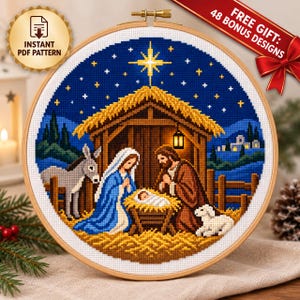 May include: A circular wooden embroidery hoop containing a cross-stitch pattern of a nativity scene. The design features a stable with a thatched roof under a dark blue starry sky with a bright yellow star, Mary, Joseph, baby Jesus, a donkey, and a lamb.