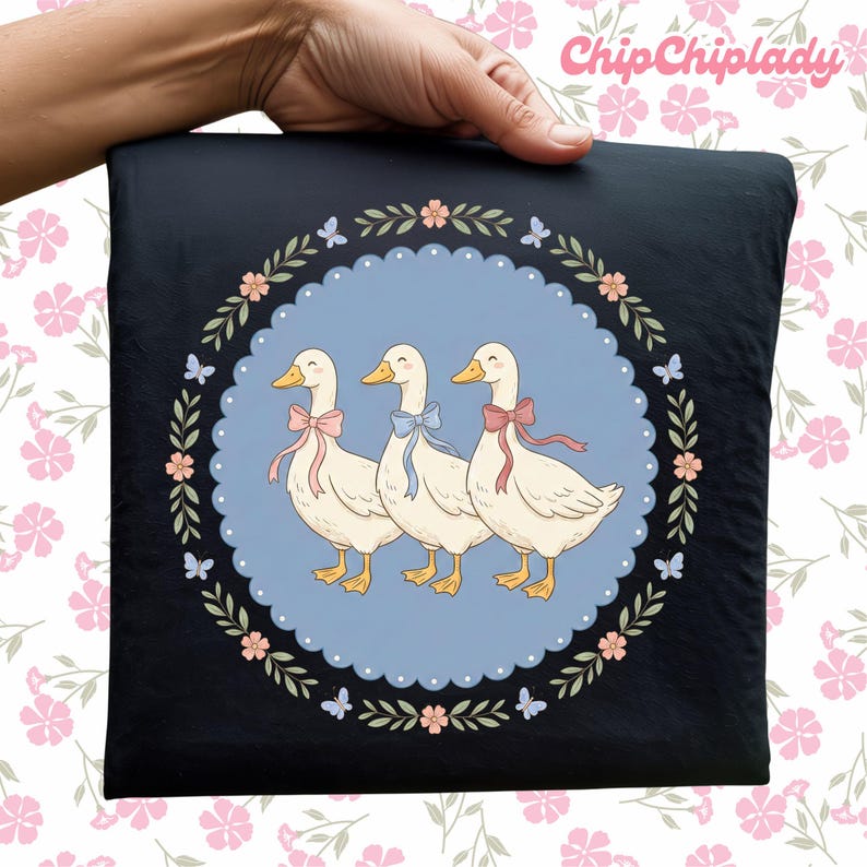 May include: Black square pillow featuring three cartoon geese with pink, blue, and pink bows, inside a blue circle with a floral border. The pillow is held by a hand, and the text "ChipChipLady" is in the upper right corner.