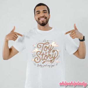 Puede incluir: Una camiseta blanca de manga corta con un dise&ntilde;o gr&aacute;fico que incluye el texto "it's a Toy Story" escrito en una fuente estilo cuerda, rodeado de ilustraciones de nubes y hojas, con el texto adicional "Baby, just say "yes"" debajo.