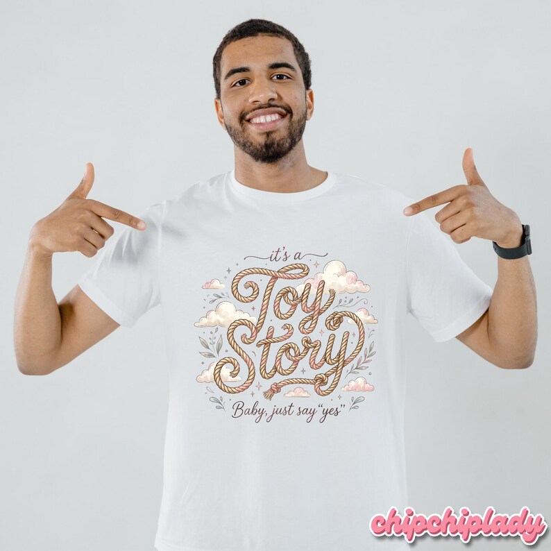 Puede incluir: Una camiseta blanca de manga corta con un dise&ntilde;o gr&aacute;fico que incluye el texto "it's a Toy Story" escrito en una fuente estilo cuerda, rodeado de ilustraciones de nubes y hojas, con el texto adicional "Baby, just say "yes"" debajo.