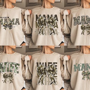 Op de afbeelding: Zes beige sweatshirts met een camouflageprint en een strikdesign. De sweatshirts hebben verschillende teksten, waaronder "Mama", "Wife" en "Glitter & Dirt Mama".