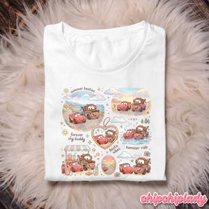 May include: White t-shirt featuring a colorful graphic of cartoon cars, including Lightning McQueen and Mater, with the phrases "summer besties," "forever my buddy," and "bestie vibes." The design includes various scenes with the cars. The shirt has a crew neck.