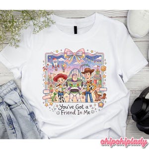 Peut inclure: T-shirt blanc avec une illustration color&eacute;e de personnages de dessin anim&eacute;. Le motif pr&eacute;sente Jessie, Buzz l'&Eacute;clair et Woody devant une sc&egrave;ne de f&ecirc;te foraine. Le texte "You've Got a Friend In Me" est &eacute;galement inclus.