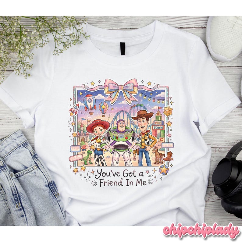 Peut inclure: T-shirt blanc avec une illustration color&eacute;e de personnages de dessin anim&eacute;. Le motif pr&eacute;sente Jessie, Buzz l'&Eacute;clair et Woody devant une sc&egrave;ne de f&ecirc;te foraine. Le texte "You've Got a Friend In Me" est &eacute;galement inclus.