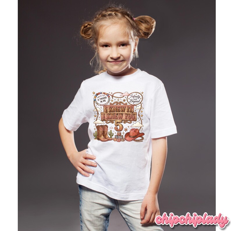 May include: A white short-sleeved t-shirt featuring a western-themed graphic with the text "I KNEW IT, I KNEW YOU", "5", "YOU'VE GOT A FRIEND IN ME", and "Infinity and Beyond". The design includes brown cowboy boots, a hat, and a lasso.