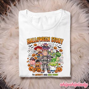 May include: White t-shirt with a Halloween-themed graphic featuring cartoon characters, pumpkins, ghosts, and bats. The text "HALLOWEEN STORY" and "TO INFINITY AND BOO-YOND!" are printed on the shirt. The shirt is displayed on a fluffy, white surface.