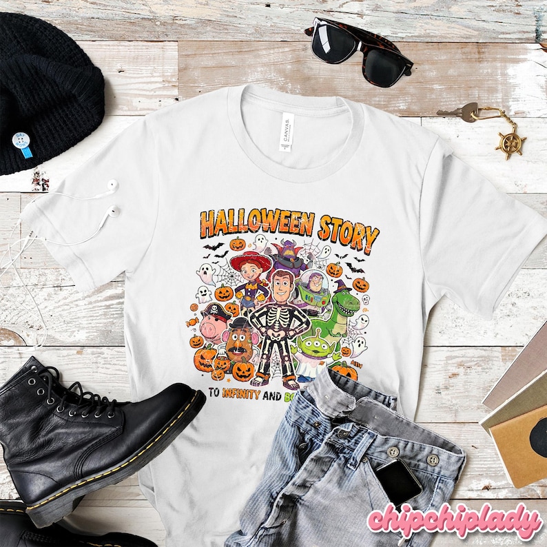 May include: White t-shirt with a colorful graphic featuring characters from Toy Story in Halloween costumes. The text "HALLOWEEN STORY" is above the characters, and "TO INFINITY AND BEYOND" is below. Includes pumpkins, ghosts, and bats.