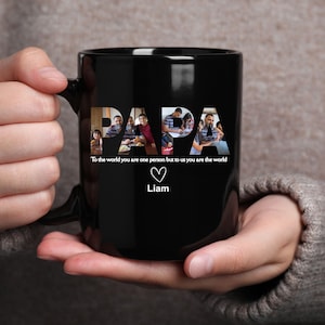 May include: Black ceramic mug with the word "PAPA" in a photo collage design. Below the word is the text "To the world you are one person but to us you are the world" with a heart and the name "Liam".
