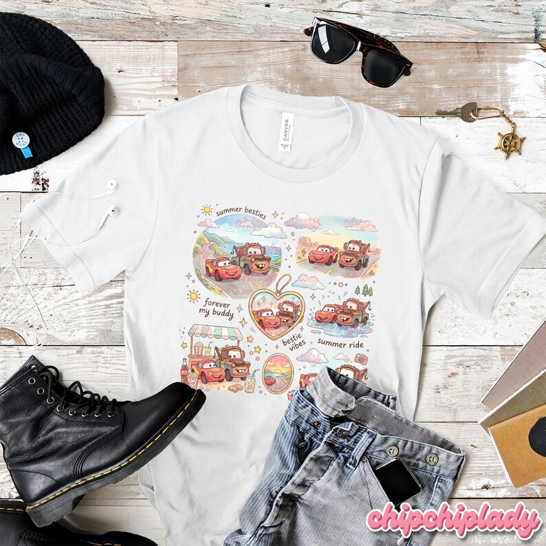 May include: White t-shirt featuring a colorful illustration of two cartoon cars, with the phrases "summer besties", "forever my buddy", and "bestie vibes". The shirt is surrounded by other items, including black boots, sunglasses, and jeans.