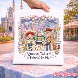 Peut inclure: Coussin carr&eacute; blanc avec une illustration color&eacute;e des personnages de Toy Story Jessie, Buzz l'&Eacute;clair et Woody. Le motif comprend des montagnes russes, des montgolfi&egrave;res et le texte "You've Got a Friend In Me". Le coussin est tenu par une main.