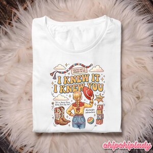 May include: A white t-shirt featuring a graphic illustration of a person with a blonde braid wearing a yellow shirt and blue jeans. The design includes cowboy boots, a red hat, alphabet blocks, and the text "I KNEW IT I KNEW YOU" and "YOU'VE GOT A FRIEND IN ME".