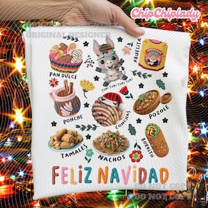 Może przedstawiać: Biała koszulka z kolorowymi haftowanymi obrazami meksykańskiego jedzenia i osła. Projekt zawiera słowa "Feliz Navidad", "Pan Dulce", "Ponche", "Tamales", "Nachos", "Pozole" i "Burrito".