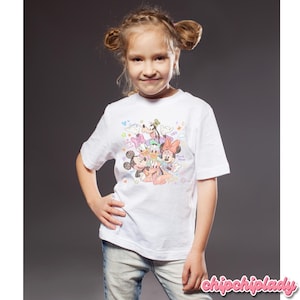 May include: A white t-shirt featuring a colorful graphic of Disney characters, including Mickey Mouse, Minnie Mouse, Donald Duck, Daisy Duck, Goofy, and Pluto. The shirt is short-sleeved and worn by a young person.