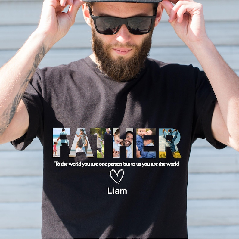 May include: Black t-shirt with the word "FATHER" in white, each letter filled with a different family photo. Below the word is the text "To the world you are one person but to us you are the world", a heart symbol, and the name "Liam".