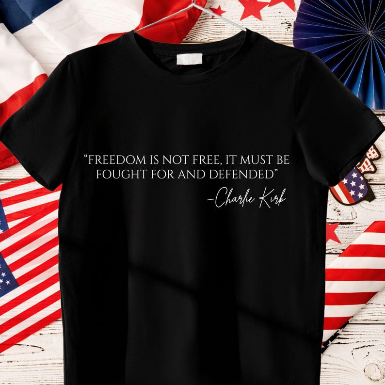 Peut inclure: T-shirt noir avec la citation "FREEDOM IS NOT FREE, IT MUST BE FOUGHT FOR AND DEFENDED" et la signature "-Charlie Kirk" en blanc. Le t-shirt est de style col rond.