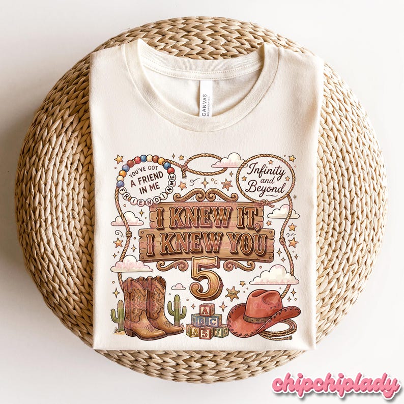 May include: A cream-colored t-shirt featuring a western-themed graphic with cowboy boots, a hat, alphabet blocks, and a lasso. The text reads: You've got a friend in me, Infinity and Beyond, and I Knew It, I Knew You 5, surrounded by stars and clouds.