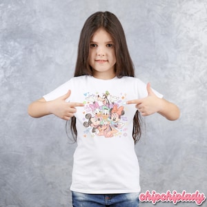 May include: White t-shirt featuring a colorful graphic of Disney characters including Mickey Mouse, Minnie Mouse, Donald Duck, Daisy Duck, Goofy, and Pluto. The design includes hearts, stars, and the words "Disney Friends".