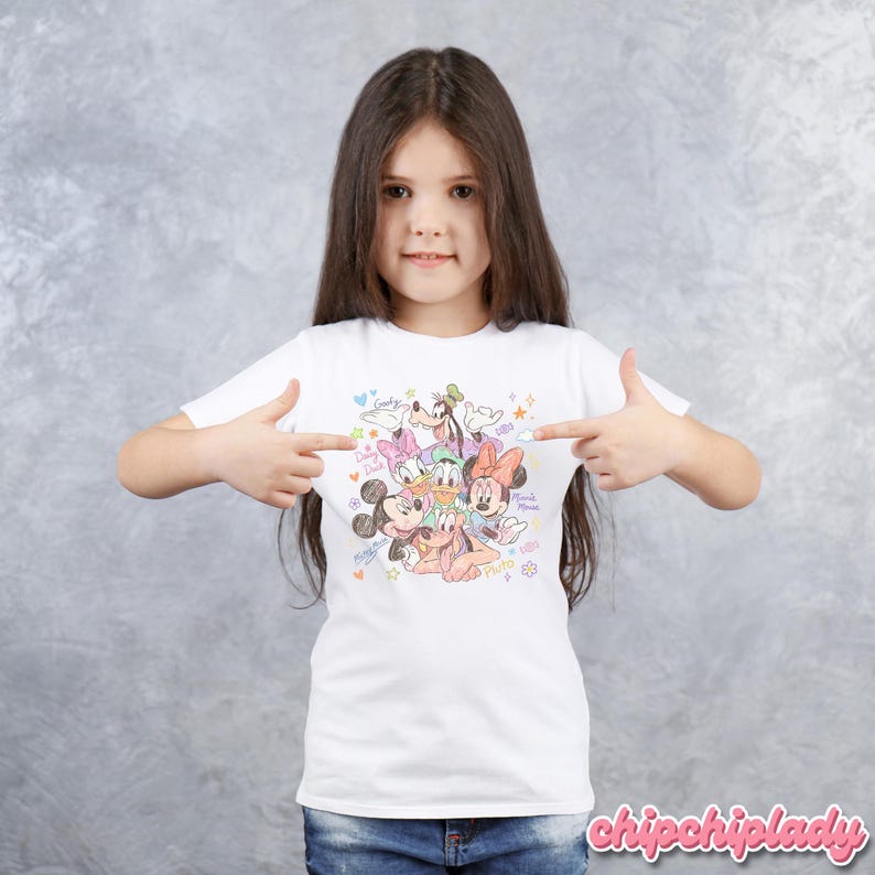 May include: White t-shirt featuring a colorful graphic of Disney characters including Mickey Mouse, Minnie Mouse, Donald Duck, Daisy Duck, Goofy, and Pluto. The design includes hearts, stars, and the words "Disney Friends".