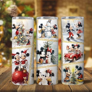 以下が含まれることがあります： クリスマスをテーマにした白いステンレス鋼タンブラー3個。各タンブラーには、クリスマスツリーの飾り付けや雪だるま作りなど、お祝いのシーンでミッキーとミニーマウスを描いた、それぞれ異なる水彩デザインが施されています。