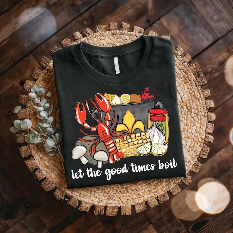 May include: Black t-shirt with a graphic of a pot of crawfish boil with the text "Let the good times boil".