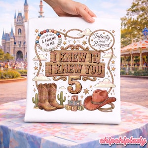 May include: A white t-shirt featuring a colorful graphic with the text "I KNEW IT, I KNEW YOU 5", "YOU'VE GOT A FRIEND IN ME", and "Infinity and Beyond". The design includes brown cowboy boots, a brown cowboy hat, alphabet blocks, and a lasso.