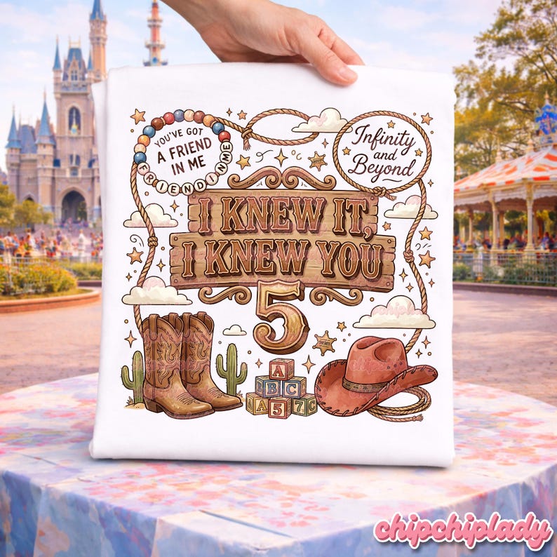 May include: A white t-shirt featuring a colorful graphic with the text "I KNEW IT, I KNEW YOU 5", "YOU'VE GOT A FRIEND IN ME", and "Infinity and Beyond". The design includes brown cowboy boots, a brown cowboy hat, alphabet blocks, and a lasso.