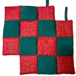 May include: A red and green quilted hot pad with a checkered pattern. The hot pad has two loops for hanging.