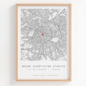 May include: Framed map print of Paris, France, in black and white, with a red heart marking a location. The print includes the text "WHERE EVERYTHING STARTED" and "I love you forever". The frame is a light wood color.