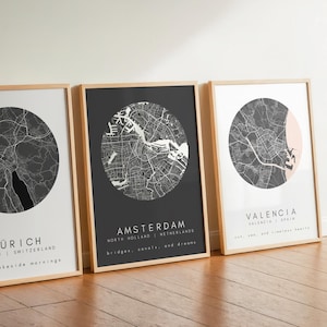 Può includere: Tre stampe di mappe di città incorniciate. Le mappe sono circolari, con un design in bianco e nero. La prima stampa dice "ZURICH" e "calm lakeside mornings". La seconda stampa dice "AMSTERDAM". La terza stampa dice "VALENCIA".