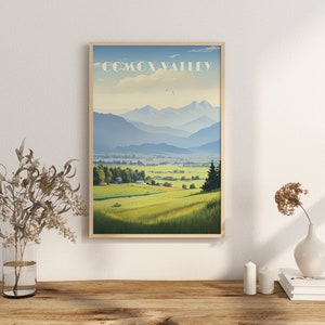 Peut inclure: Une affiche encadrée de la vallée de Comox, avec des champs verts, des montagnes et un ciel bleu. L'affiche est dans un cadre en bois clair et porte le texte "COMOX VALLEY" en haut. L'œuvre d'art évoque la paix et la beauté naturelle.