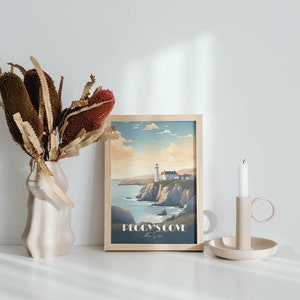 K&ouml;nnte beinhalten: Ein gerahmter Druck eines Leuchtturms auf einer Klippe mit Blick auf das Meer. Der Druck tr&auml;gt den Titel "Peggy's Cove, Nova Scotia". Der Druck wird auf einer wei&szlig;en Oberfl&auml;che mit einer Vase mit getrockneten Blumen und einem Kerzenhalter angezeigt.