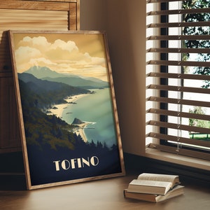 K&ouml;nnte beinhalten: Ein gerahmtes Poster mit einer Illustration im Vintage-Stil einer K&uuml;stenlandschaft. Das Poster zeigt eine Bergkette, einen Strand und eine Wasserfl&auml;che. Der Text "TOFINO" ist unten auf dem Poster in Wei&szlig; gedruckt.