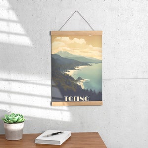 K&ouml;nnte beinhalten: Ein Vintage-Poster mit einer malerischen Aussicht auf eine K&uuml;ste mit Bergen im Hintergrund. Das Poster hat einen Holzrahmen und den Text "TOFINO" unten.