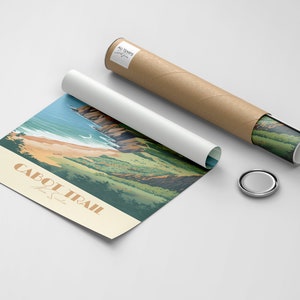 May include: A rolled up poster featuring a scenic view of the Cabot Trail in Nova Scotia. The poster is brown and depicts a blue ocean, green trees, and a sandy beach. The text "CABOT TRAIL Nova Scotia" is printed on the poster.
