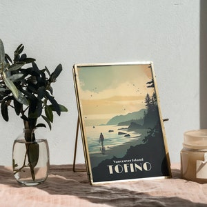 May include: A gold-framed picture with a vintage-style illustration of a beach scene with a person walking on the shore. The text on the picture reads "Vancouver Island Tofino".