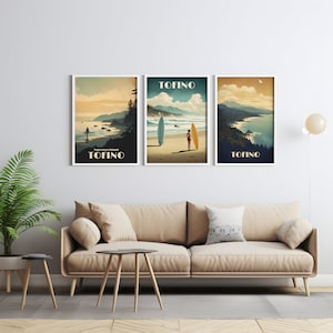 K&ouml;nnte beinhalten: Drei gerahmte Drucke einer Strandszene mit dem Wort "TOFINO" auf jedem. Die Drucke h&auml;ngen an einer wei&szlig;en Wand &uuml;ber einem hellbraunen Sofa.