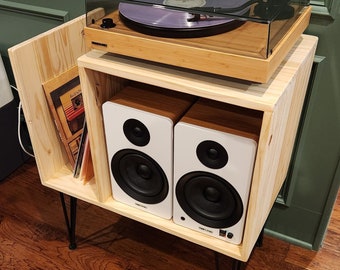 May include: A wooden record player stand with a turntable and two white speakers. The stand has black hairpin legs and a shelf for storing records.