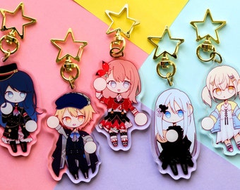 Könnte beinhalten: Fünf bunte Anime-Charakter-Schlüsselanhänger mit goldenen sternförmigen Anhängern. Jeder Schlüsselanhänger zeigt einen anderen Charakter mit einzigartigen Kleidungsstücken und Frisuren.