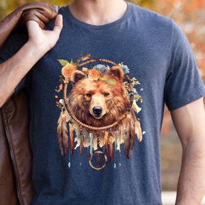 May include: A navy blue t-shirt with a brown bear face inside a dreamcatcher with feathers and flowers.