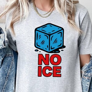 May include: A light gray t-shirt featuring a blue ice cube graphic with the words "NO ICE" in red. The ice cube has diagonal lines and is dripping black liquid. The shirt is a casual style.
