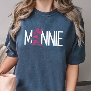 May include: A navy blue t-shirt with a white graphic of Minnie Mouse and the text "MINNIE" in white.
