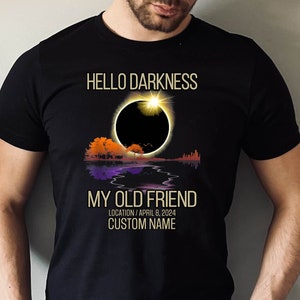 May include: Black t-shirt with a graphic of a solar eclipse and the text "Hello Darkness My Old Friend" with the date "April 8, 2024" and the text "Location/Custom Name".