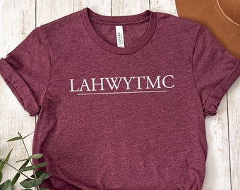 Può includere: Una maglietta color granata con la scritta "LAHWYTM" stampata in bianco sul davanti.