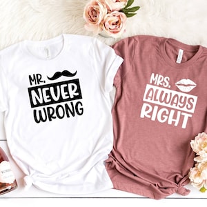 May include: Two t-shirts with a humorous couple's message. The white t-shirt says "Mr. Never Wrong" with a black mustache icon. The pink t-shirt says "Mrs. Always Right" with a white lipstick icon.
