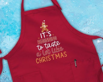 Könnte beinhalten: Rote Weihnachts-Schürze mit einem Lebkuchenmann-Motiv und dem Text "It's beginning to taste a lot like Christmas".