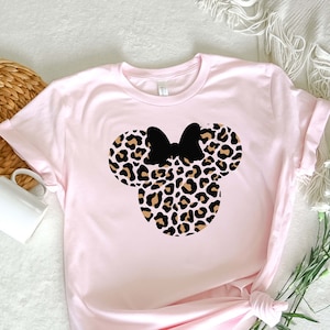 May include: A pink t-shirt with a leopard print Minnie Mouse head design. The ears and bow are black.