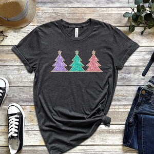 May include: A dark grey t-shirt with a design of three glitter Christmas trees in purple, teal, and pink.