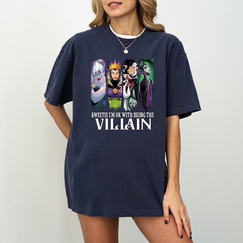Pu&ograve; includere: T-shirt blu navy con una grafica di quattro cattivi dei cartoni animati e la scritta "Sweetie I'm OK with Being the Villain". La grafica include Ursula, la Regina Cattiva, Crudelia De Mon e Malefica.